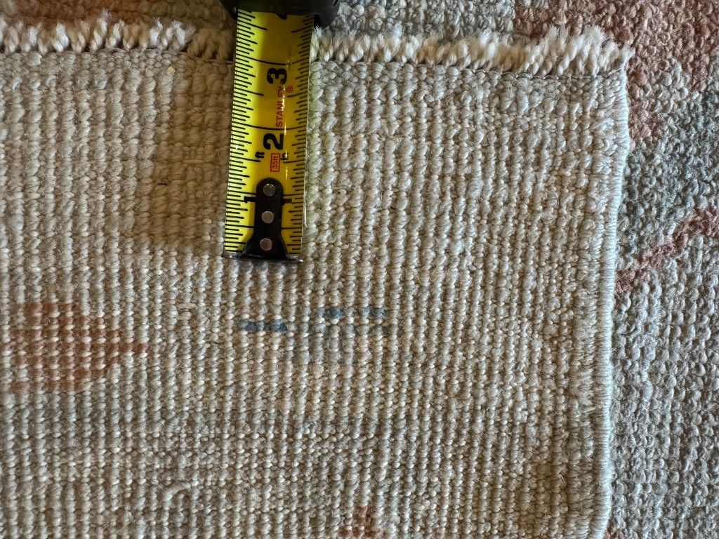 Back of a coarser hand-knotted rug with a tape measure showing knot count