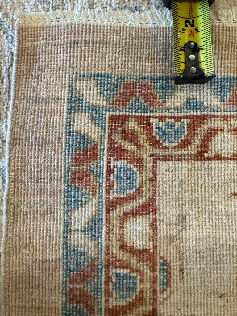 Back of a finely hand-knotted rug with a tape measure showing knot count