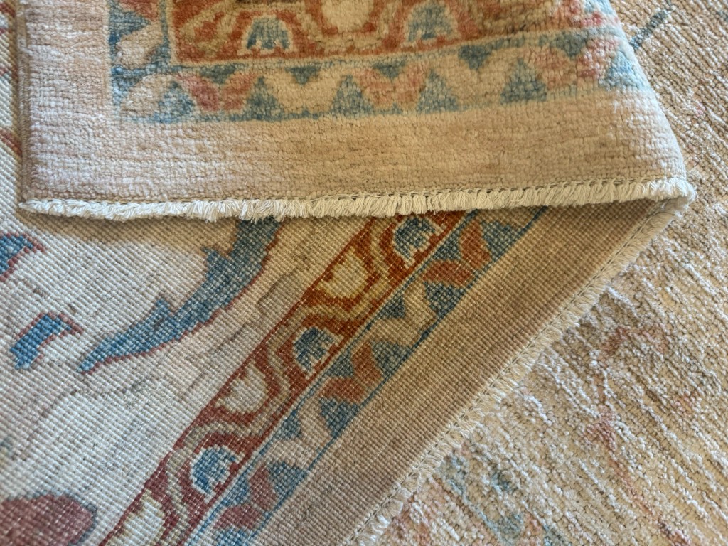 Corner of a hand-knotted rug folded back to show the weave and selvedge